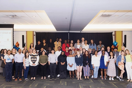 Group of men and women posing for picture inside a conference room